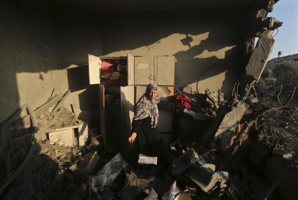 Palestinian woman inspects her house which police said was damaged in an Israeli air strike on a neighbouring house in Gaza City