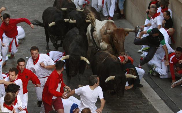 Runners sprint alongside Dolores Aguirre fighting bulls on Santo Domingo street, during the second running of the bulls of the San Fermin festival in Pamplona