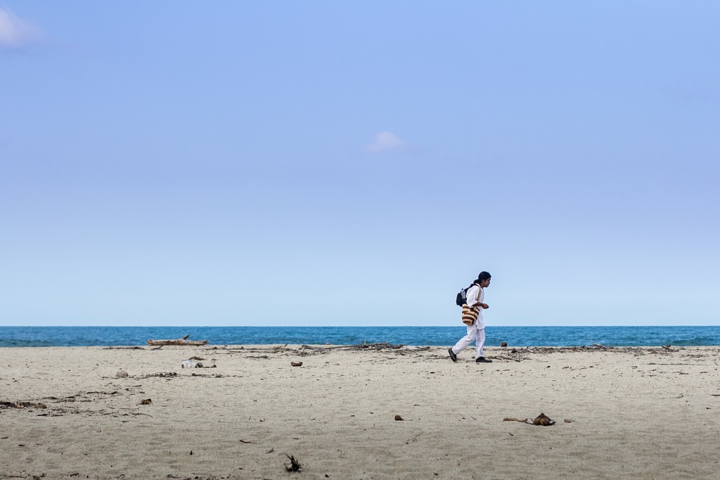  Ένας ιθαγενής περπατάει κατά μήκος της θάλασσας με την κολομβιανή παραδοσιακή τσάντα “mochila” κρεμασμένη στον ώμο.